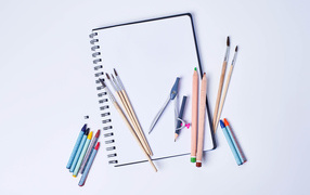 Notepad with pencils and brushes on a white background