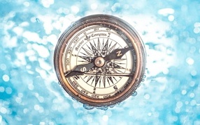 Old compass in the water on a blue background