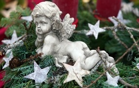 The figurine of an angel lies on the branches of a thuja