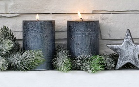 Two large lit candles against the wall