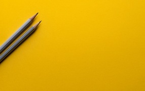 Два карандаша на желтом фоне