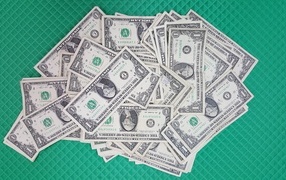 A lot of one dollar bills on a green surface