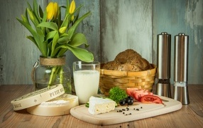 Сыр с овощами на столе с хлебом и букетом тюльпанов