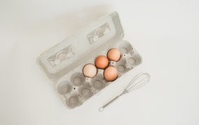 Четыре яйца в лотке на сером фоне