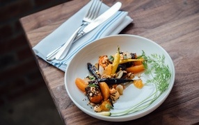 Жареные овощи на тарелке со столовыми приборами