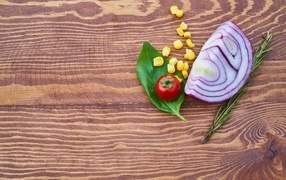 Половина лука на столе с кукурузой и помидором