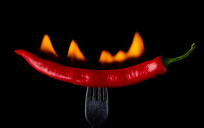 Жгучий красный перец на вилке на черном фоне