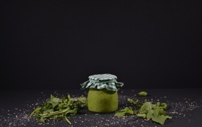Банка соуса песто на черном фоне