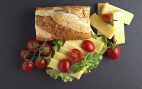 Батон с сыром и помидорами на сером фоне