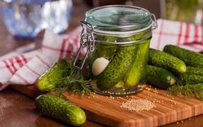 Pickled cucumbers in a jar on the table with fresh