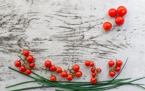 Красные помидоры с зеленым луком на деревянном столе