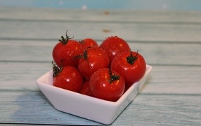 Красные мокрые помидоры в белой тарелке