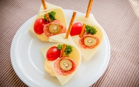 Sandwiches with sausage, cheese and tomatoes on a white plate