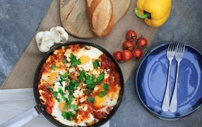 Scrambled eggs on the table with vegetables and loaf