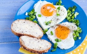 Яичница с бутербродами и зеленым луком на тарелке