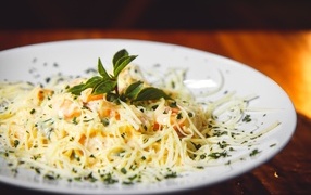 Спагетти с сыром и помидорами на белой тарелке
