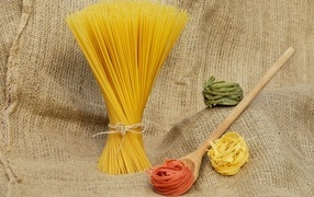 Спагетти с деревянной ложкой и макаронами на столе 
