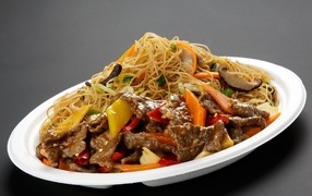 Острая лапша с грибами на белой тарелке на сером фоне