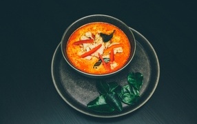 Острый суп в тарелке на черном фоне
