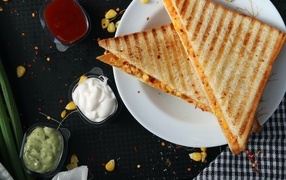 Два сэндвича на тарелке на столе с соусом