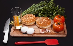 Vegetables, eggs, greens and buns on a black background