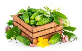 Wooden box with green cucumbers and spices