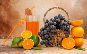 Basket with grapes on the table with oranges and lime