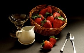 Корзина со спелой красной клубникой на столе с посудой