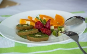Fresh sliced fruits on a plate with a fork