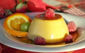 Желе в карамели на тарелке с ягодами малины и апельсином