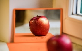 Больше красное яблоко отражается в зеркале 