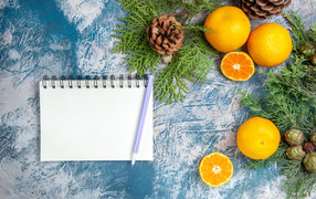 Блокнот на столе с мандаринами и ветками
