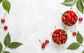 Спелая красная вишня с зелеными листьями на столе