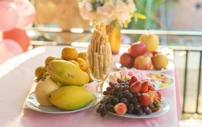 Спелые сладкие фрукты и ягоды на столе с трубочками