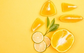 Sliced orange and lime fruits on yellow background