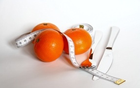 Tangerines with centimeter and cutlery on white background