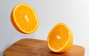 Two halves of an orange on a wooden board