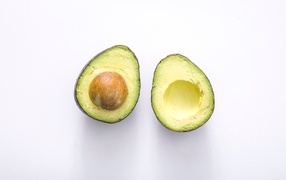 Two halves of green avocado on a gray background