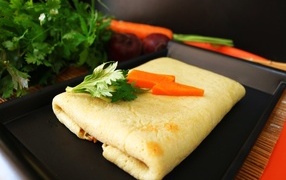 Pancake on a plate with carrots and parsley sprigs
