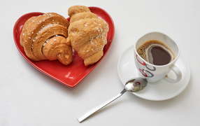 Two croissants with a cup of coffee on a gray background