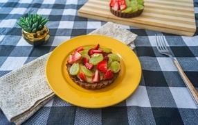 Пирожное с кремом и ягодами клубники и винограда