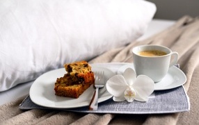 Пирожное на постели с чашкой кофе и цветком