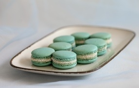 Зеленый десерт макаронс на большой тарелке на столе