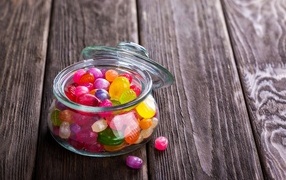 Multi-colored candies in a glass jar on the table