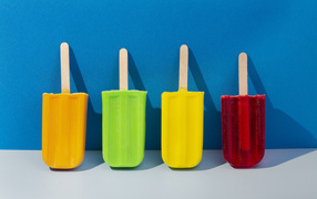 Multi-colored popsicles on a blue wall background
