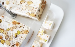 Нуга с орехами на белой тарелке