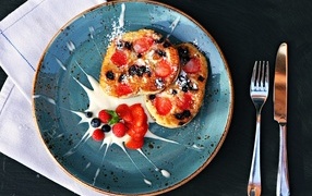 Pancakes on a plate with berries and sour cream