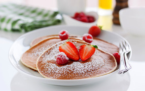 Pancakes on a plate with powdered sugar and strawberries