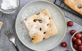 Кусок вишневого пирога на тарелке с сахарной пудрой