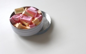 Розовые и оранжевые конфеты в коробке на сером фоне
